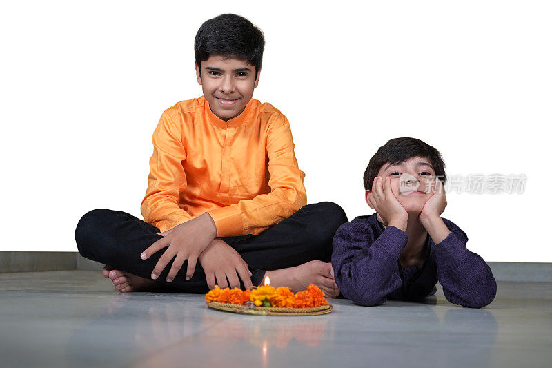 两个微笑的印度亚洲男孩与一个Pooja或祈祷塔利与Jyot, Diya, Deepak火焰和金盏花孤立在白色的背景